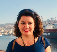 Mujer sonriendo junto a un cuerpo de agua
Descripción generada automáticamente